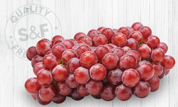 Cluster of fresh red seedless grapes with water droplets, displayed on a light background for a produce promotion.