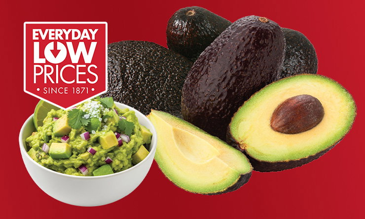 Whole Hass avocados next to a halved avocado showing green flesh and pit